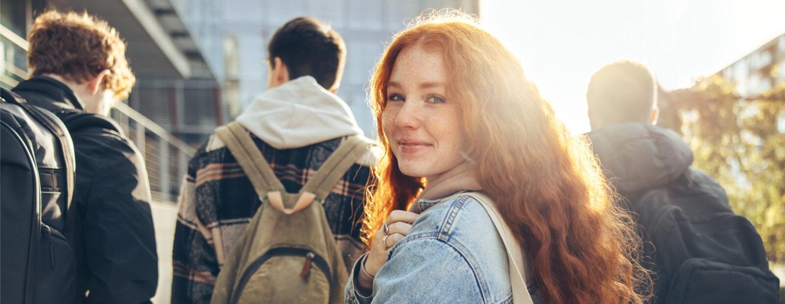 College students walking outside with girl smiling back at camera